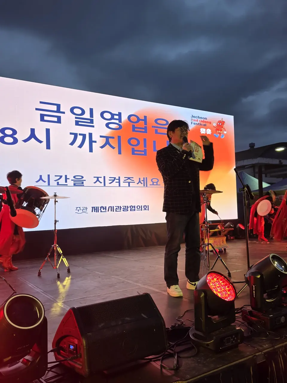 저녁 야외 무대에서 마이크를 들고 진행하는 MC