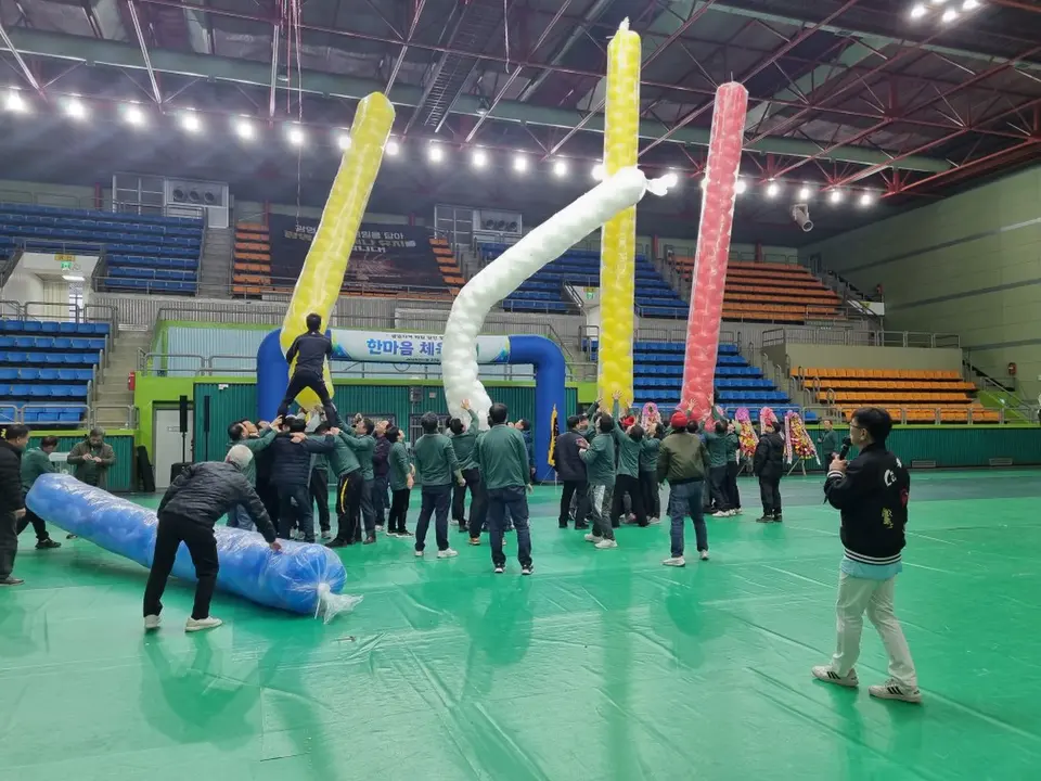 체육관 바닥에서 대형 풍선 소품으로 게임을 하는 참가자들