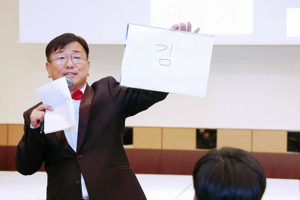 종이를 들고 마이크로 진행하는 MC 신용주 클로즈업