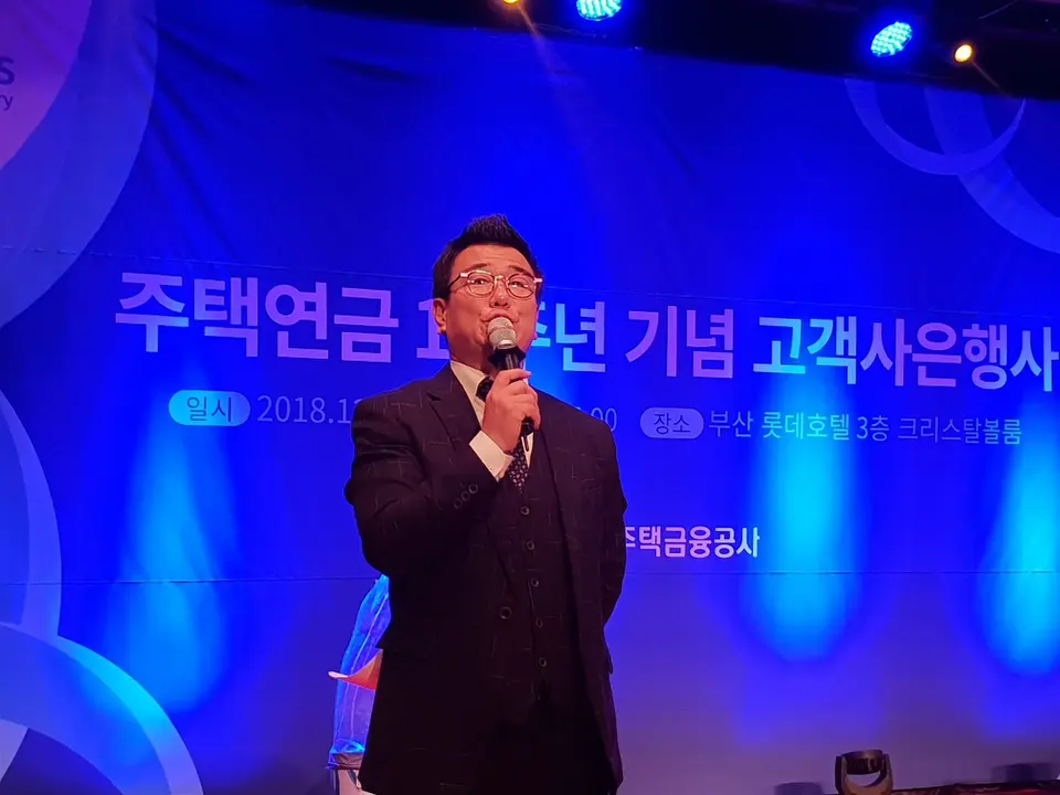 파란 조명의 무대에서 마이크로 사회를 진행하는 MC