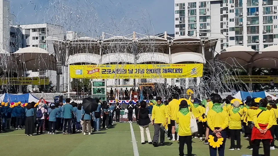 운동장 스탠드 앞에 모인 노란 복장의 대규모 참가자들