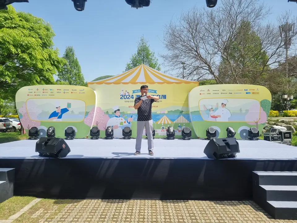 야외 무대 위에서 마이크로 진행하는 MC